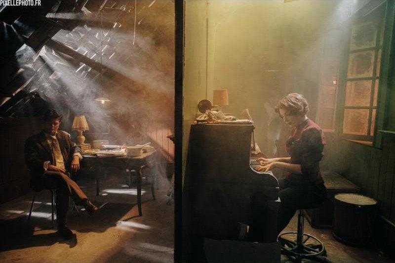 Lumière dorée et fumée sur deux plateaux, autour d'une table et d'un piano.