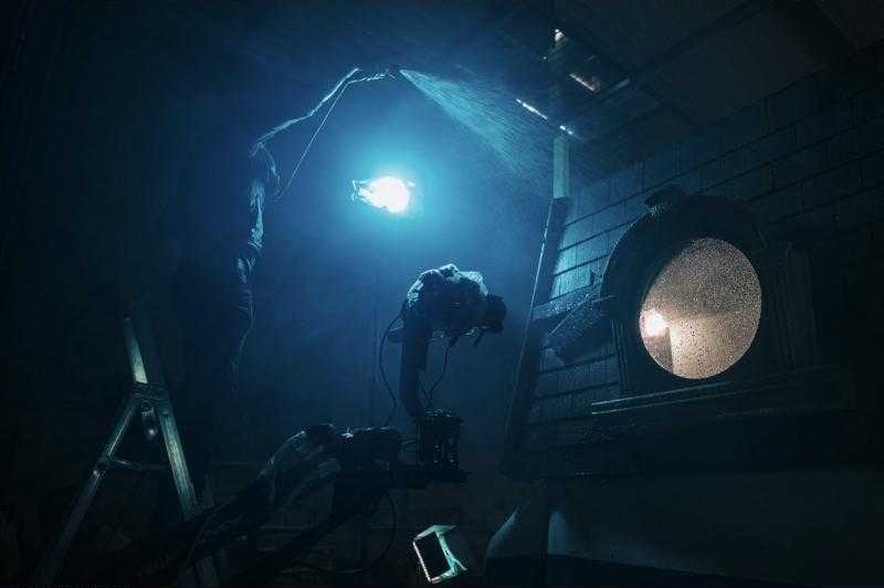 Un plateau plongé dans la lumière bleue, un projecteur derrière un hublot.
