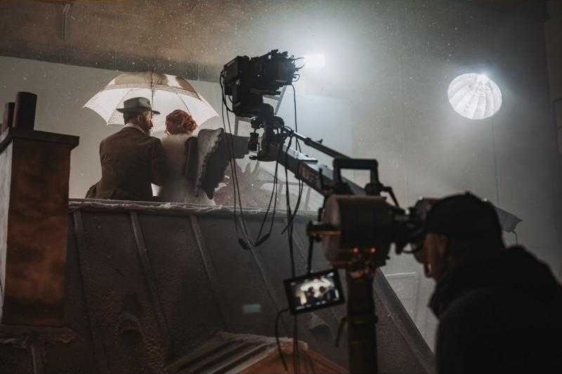 Une caméra de cinéma sur grue, face à un décor de toits.